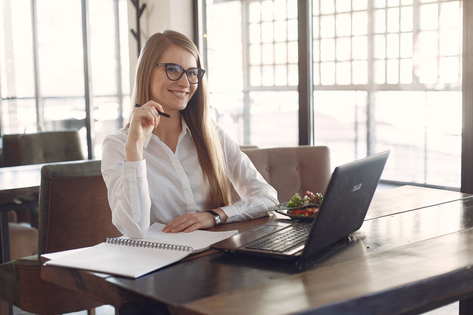 A partner working at a cafe table with her laptop and notebook